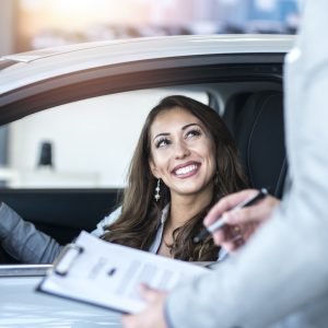 Happy customer buying brand new car at local car dealership.